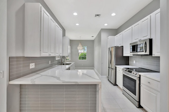 kitchen with white cabinets, a peninsula, stainless steel appliances, pendant lighting, and a sink