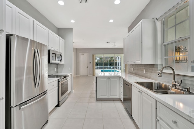 kitchen with light tile patterned floors, stainless steel appliances, light countertops, white cabinets, and a sink