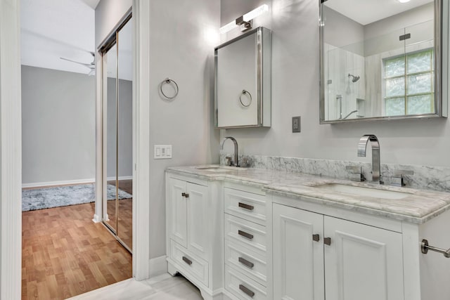 bathroom featuring ceiling fan, double vanity, wood finished floors, and a sink