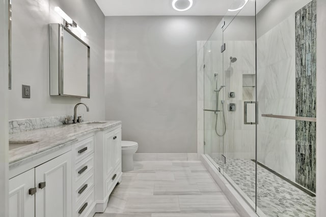 bathroom with a shower stall, toilet, a sink, double vanity, and baseboards