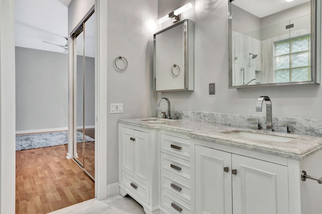 full bath with walk in shower, double vanity, a sink, and wood finished floors