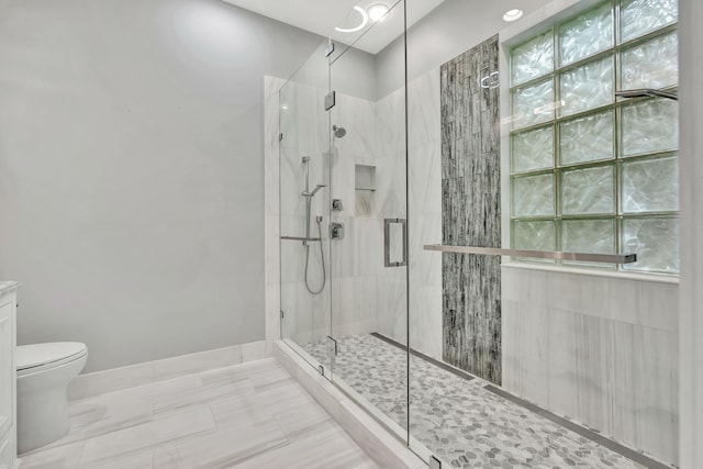 bathroom with toilet, baseboards, and a stall shower