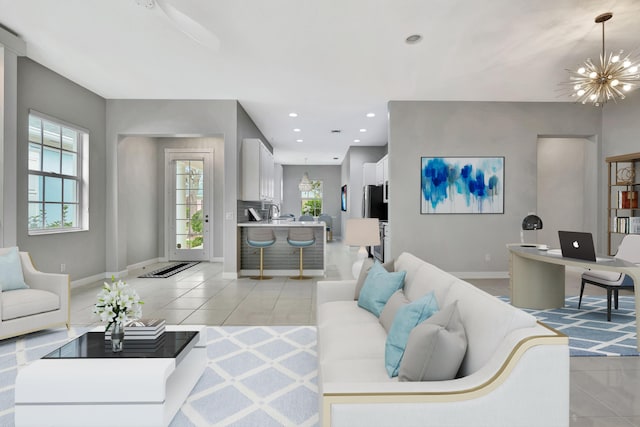 living room with plenty of natural light, a notable chandelier, baseboards, and light tile patterned flooring