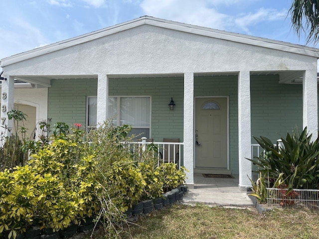 doorway to property featuring a porch and stucco siding