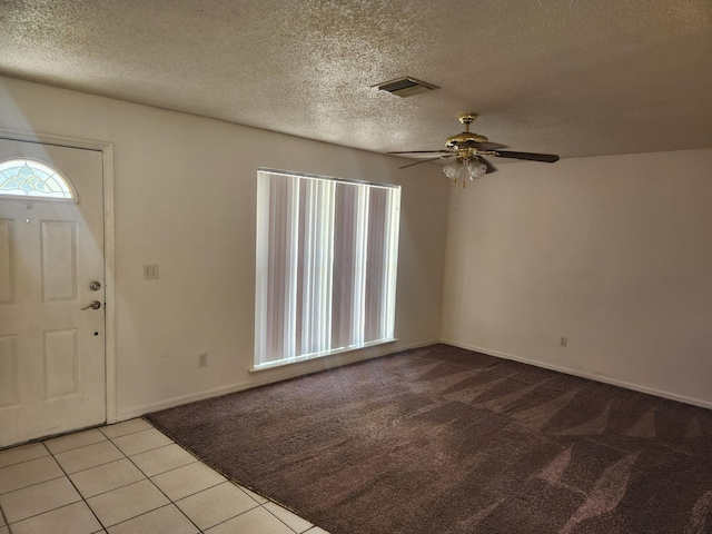 entryway featuring light tile patterned floors, ceiling fan, a textured ceiling, light colored carpet, and visible vents