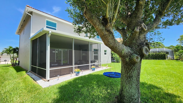 back of house with a lawn, a sunroom, and stucco siding