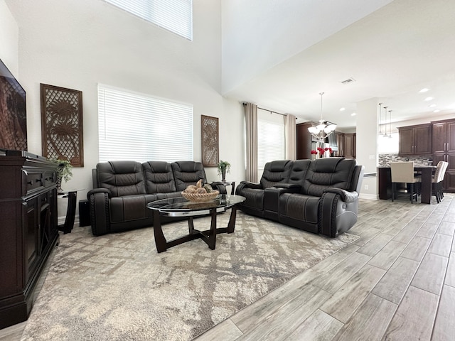 living room with a notable chandelier, recessed lighting, a towering ceiling, wood tiled floor, and baseboards