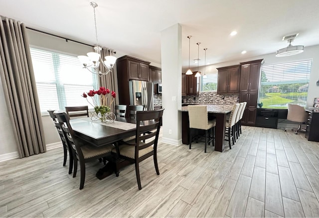 dining area with light wood-style flooring, visible vents, a chandelier, and a wealth of natural light