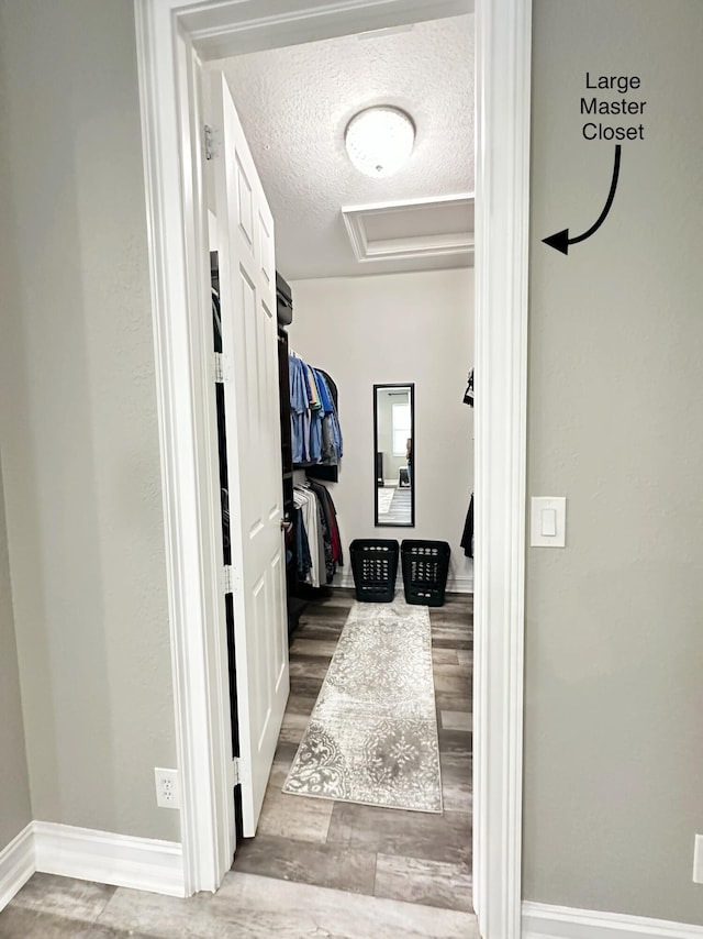 walk in closet with wood finished floors and attic access