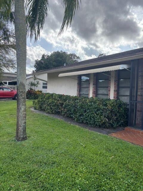 view of side of property with a lawn and stucco siding