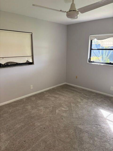 carpeted spare room with a ceiling fan and baseboards