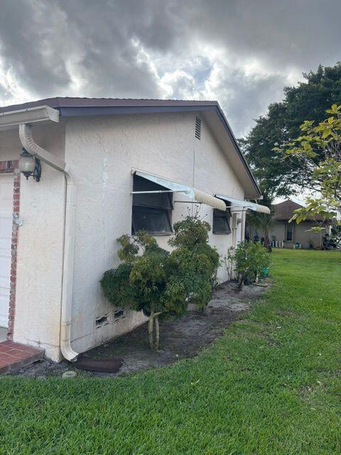 view of side of home with a yard and stucco siding