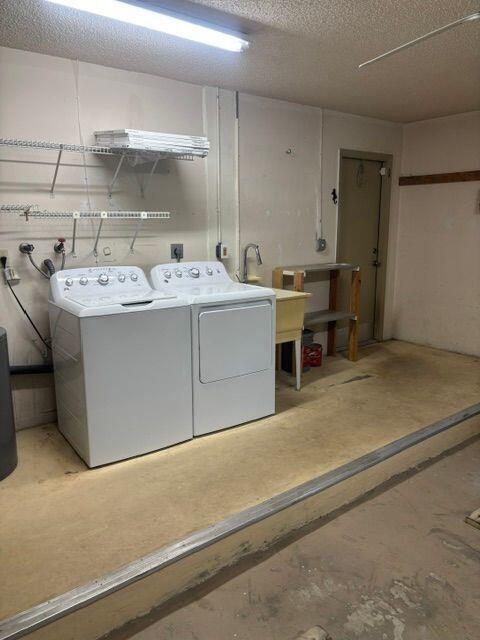 clothes washing area featuring laundry area, washer and clothes dryer, and a textured ceiling