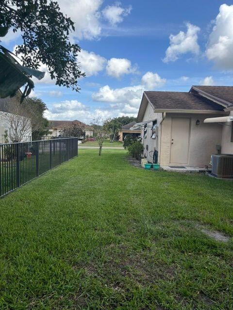 view of yard featuring fence and central AC unit