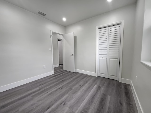 unfurnished bedroom with a closet and dark hardwood / wood-style flooring