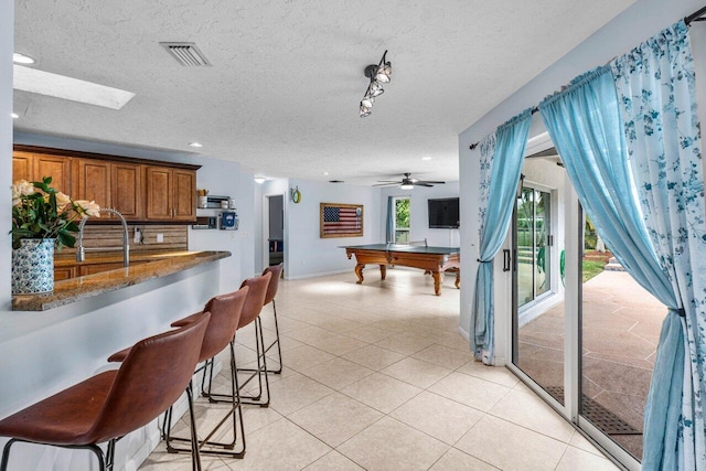 interior space featuring visible vents, baseboards, pool table, light tile patterned floors, and a textured ceiling