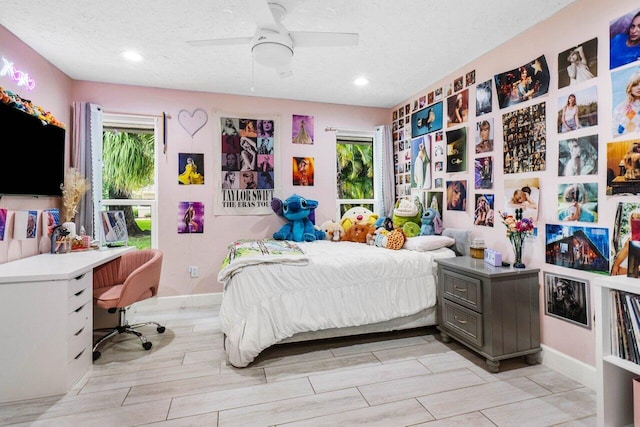 bedroom with baseboards, ceiling fan, wood tiled floor, and a textured ceiling