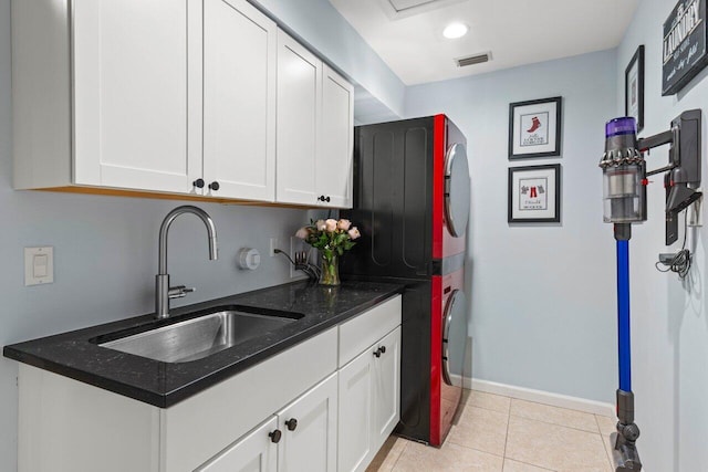 kitchen featuring stacked washing maching and dryer, visible vents, white cabinetry, and a sink