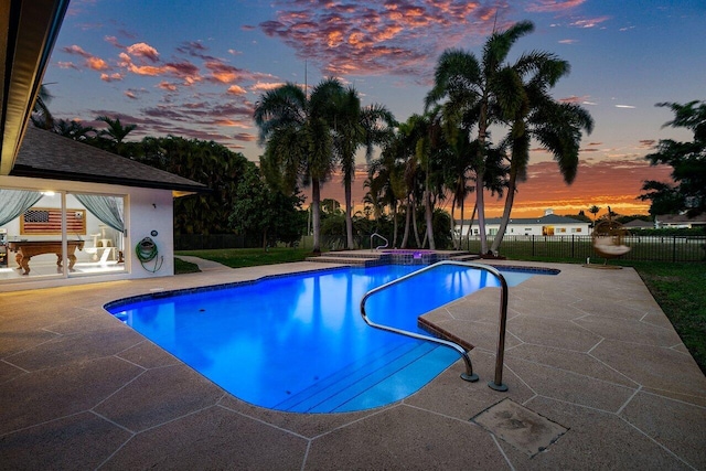 pool at dusk featuring fence, a patio area, and a fenced in pool