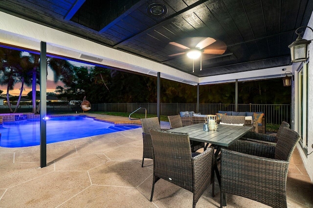 pool at dusk with a ceiling fan, outdoor dining space, outdoor lounge area, a patio, and a fenced backyard