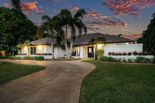 view of front of property with fence, concrete driveway, and a lawn