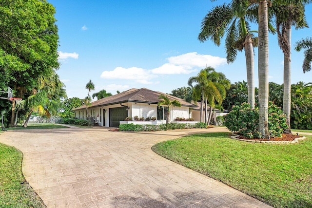 view of front of home featuring an attached garage, decorative driveway, and a front yard