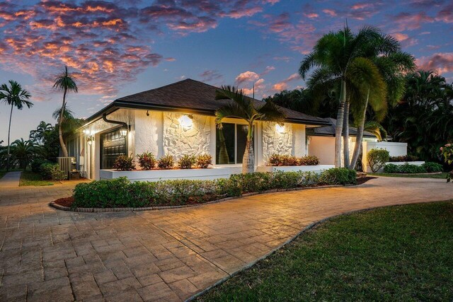 entrance to property with roof with shingles, french doors, stucco siding, and stone siding