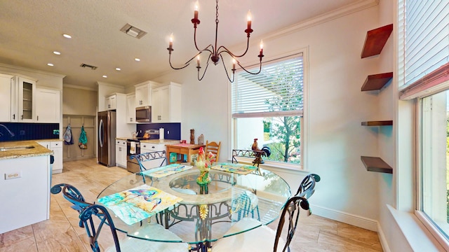 dining room with sink, ornamental molding, and an inviting chandelier