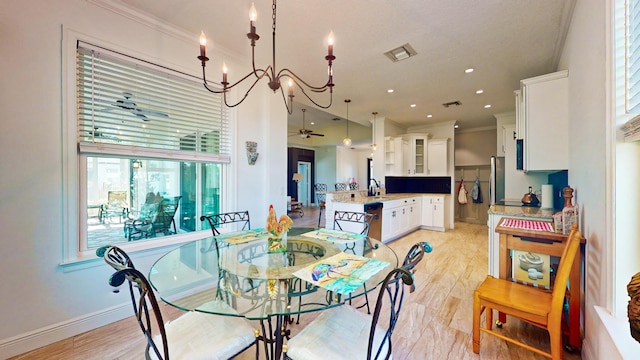 dining space featuring ceiling fan with notable chandelier, light wood-type flooring, sink, and ornamental molding