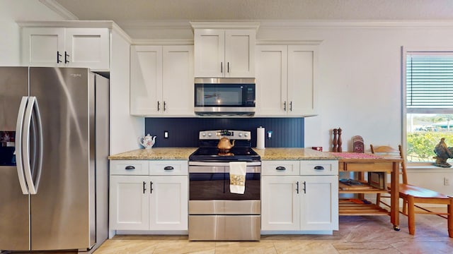 kitchen featuring light stone counters, a textured ceiling, crown molding, stainless steel appliances, and white cabinets