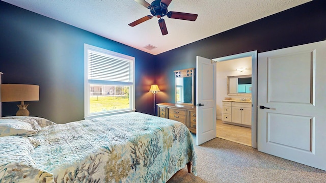 carpeted bedroom featuring ensuite bath, ceiling fan, and a textured ceiling