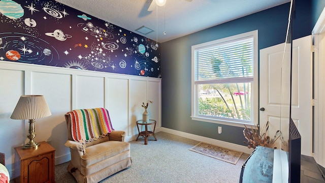 sitting room with ceiling fan, carpet floors, and a textured ceiling