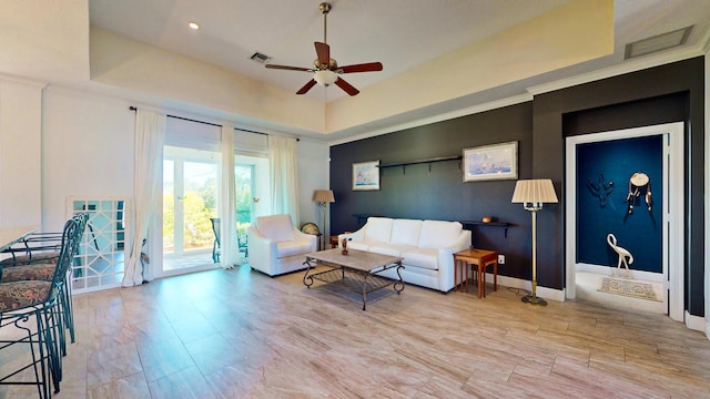 living room featuring a raised ceiling and ceiling fan