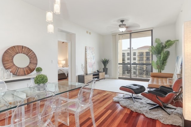 sitting room with a wall of windows, ceiling fan, and wood finished floors