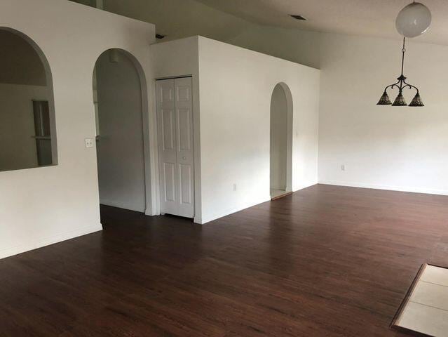 spare room with high vaulted ceiling and dark hardwood / wood-style floors