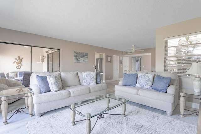 living room featuring a textured ceiling, light hardwood / wood-style floors, and ceiling fan