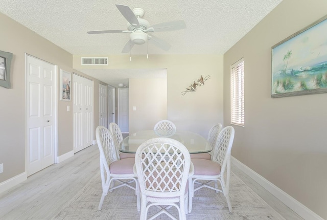 dining space with light wood-type flooring, ceiling fan, and a textured ceiling