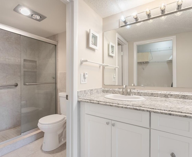 bathroom featuring a shower with door, tile patterned floors, toilet, a textured ceiling, and vanity