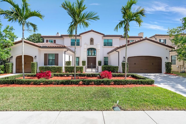 mediterranean / spanish-style house featuring a front yard, driveway, an attached garage, and stucco siding