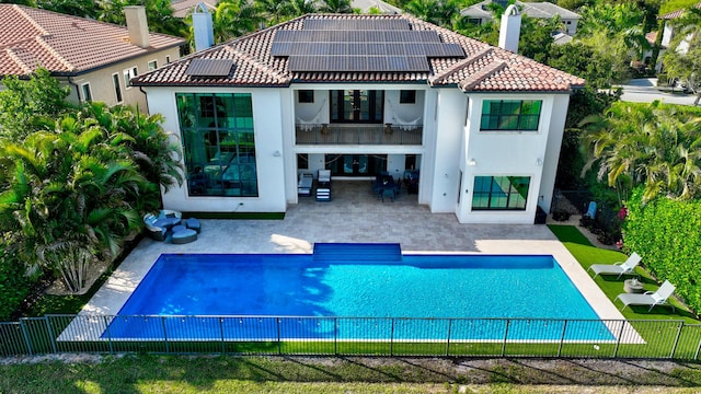 rear view of house featuring a tile roof, a patio area, a fenced backyard, and a balcony