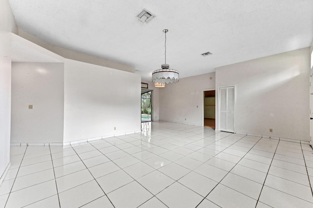 unfurnished room featuring light tile patterned floors, visible vents, and a notable chandelier