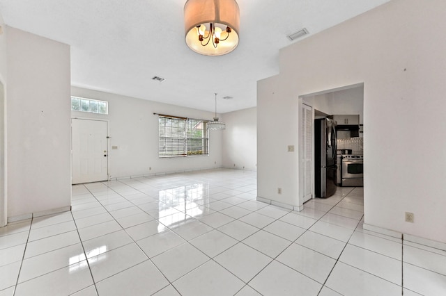 spare room featuring visible vents, a notable chandelier, and light tile patterned flooring