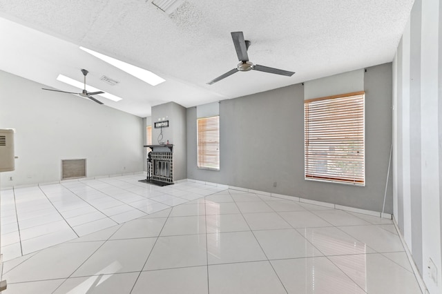 unfurnished living room with a ceiling fan, visible vents, lofted ceiling with skylight, and tile patterned floors