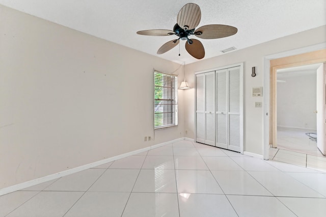 unfurnished bedroom featuring a closet, visible vents, light tile patterned flooring, a textured ceiling, and baseboards