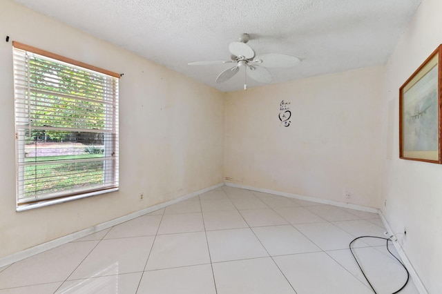 unfurnished room featuring light tile patterned floors, a textured ceiling, baseboards, and a ceiling fan