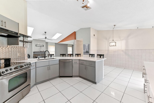 kitchen featuring visible vents, gray cabinetry, appliances with stainless steel finishes, a sink, and under cabinet range hood