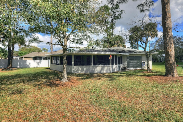 back of house featuring a sunroom, fence, and a yard