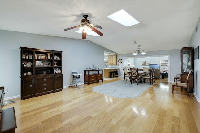 2103 SE Meadowbrook Rd, Stuart, FL 34997 - living area with lofted ceiling with skylight, baseboards, light wood finished floors, and ceiling fan with notable chandelier