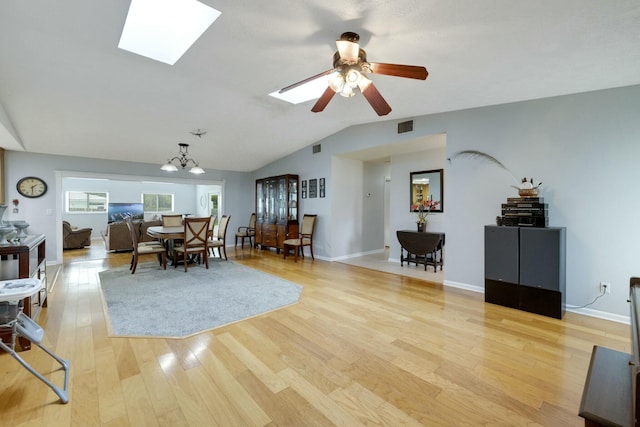 2103 SE Meadowbrook Rd, Stuart, FL 34997 - dining room with light wood finished floors, visible vents, vaulted ceiling with skylight, baseboards, and ceiling fan with notable chandelier