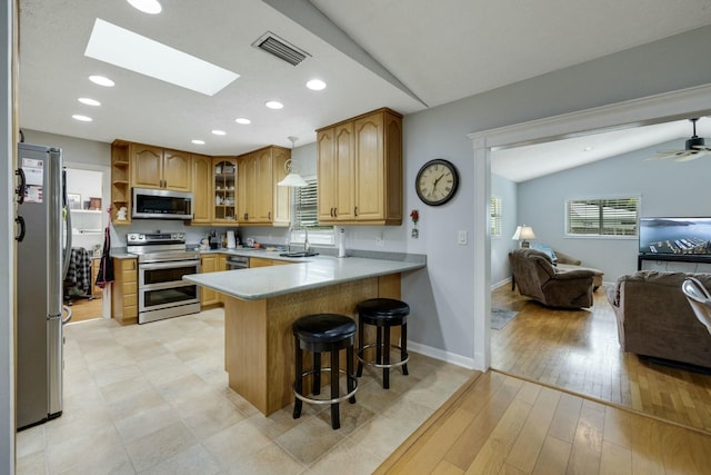 2103 SE Meadowbrook Rd, Stuart, FL 34997 - kitchen with a peninsula, open floor plan, appliances with stainless steel finishes, a kitchen bar, and glass insert cabinets
